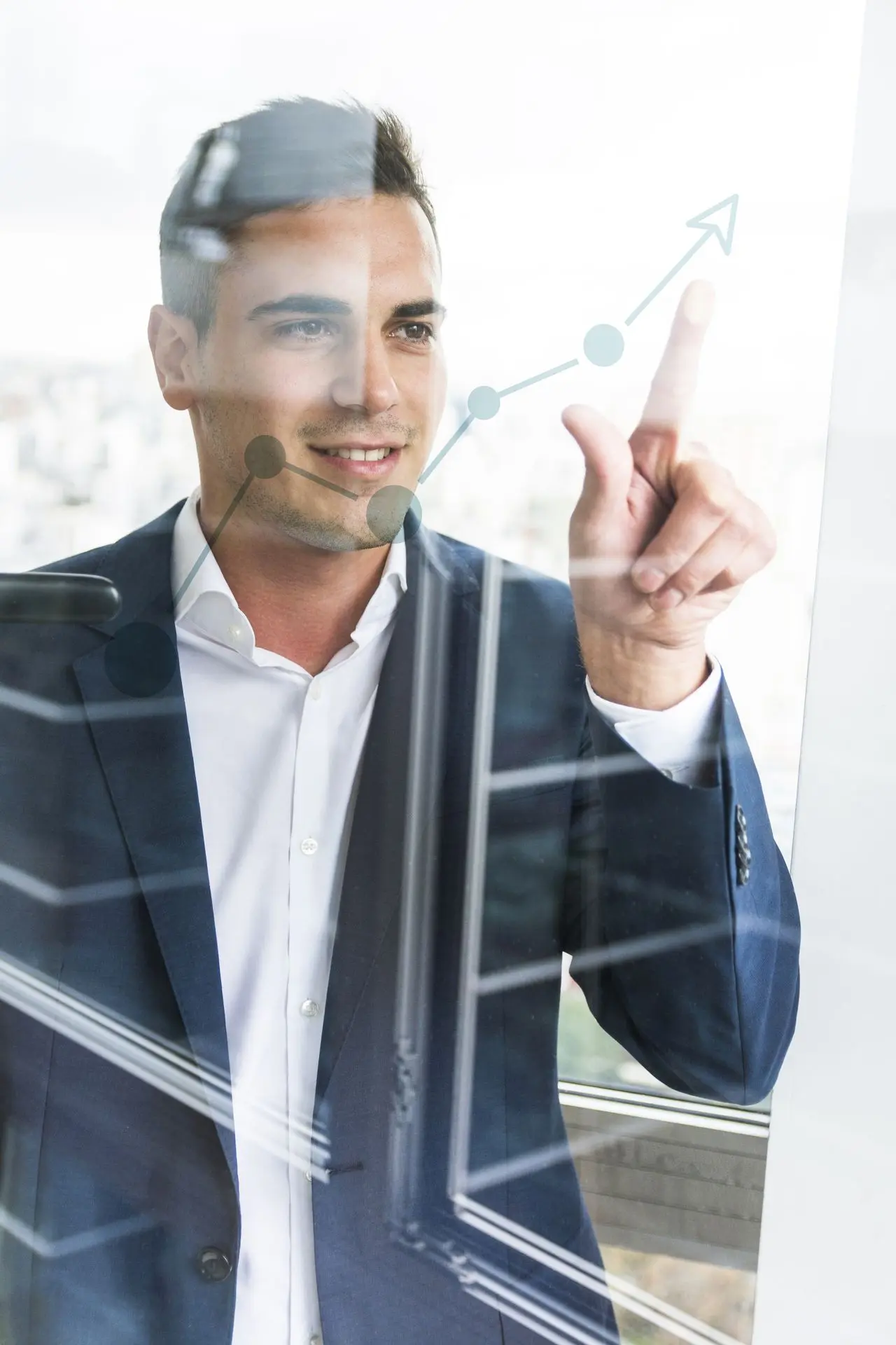 Hombre de negocios joven sonriente señalando el aumento de un gráfico bursátil en un vidrio transparente