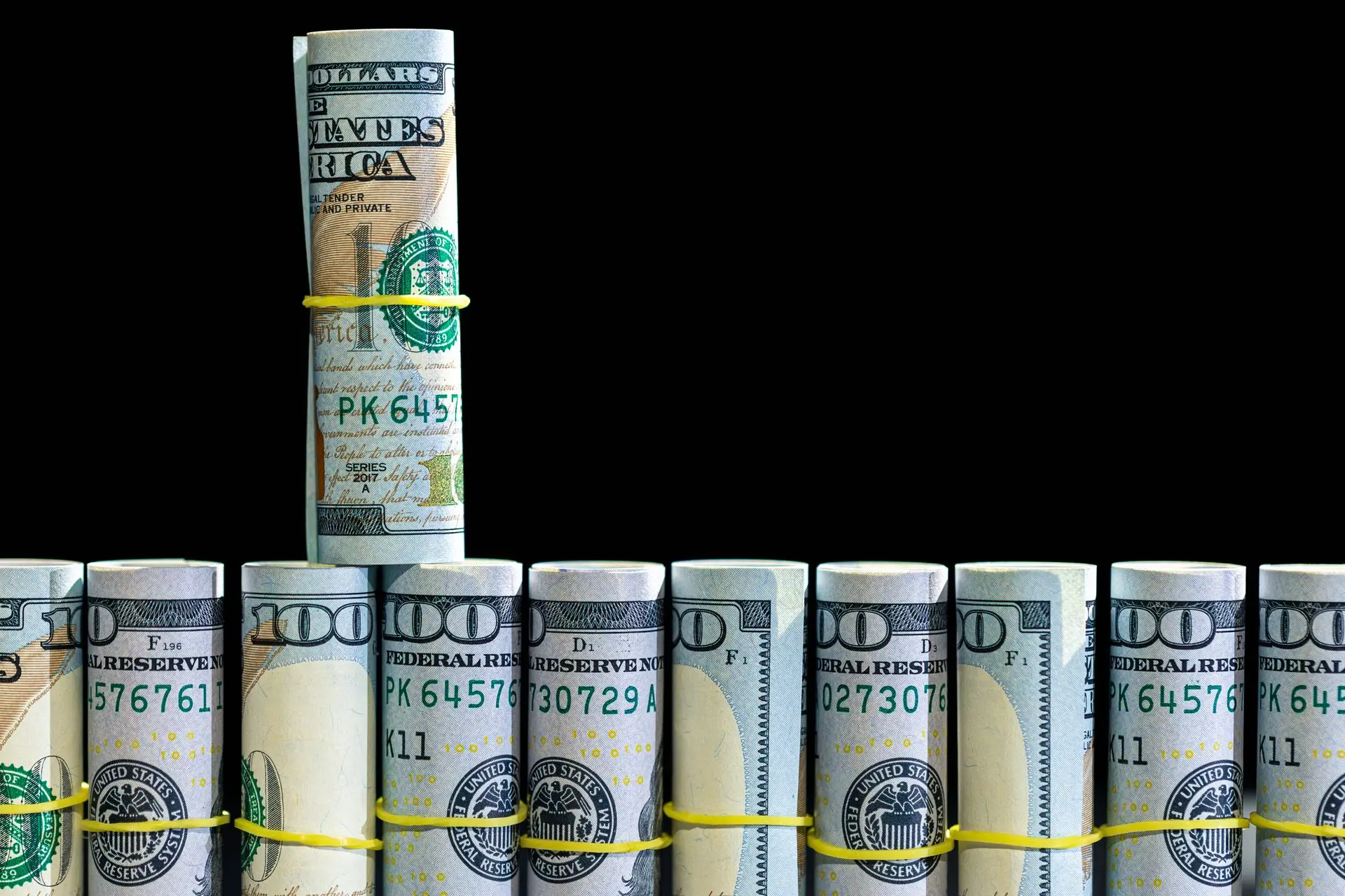 Billetes de 100 dólares retorcidos sobre un fondo negro, concepto financiero